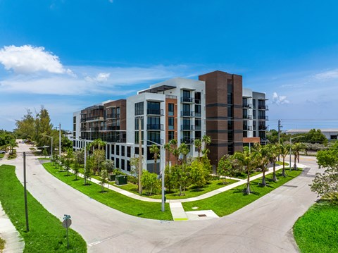 A modern multi-story building with a parking lot in front.