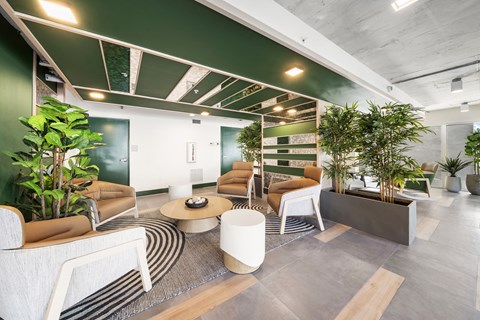 A modern office space with a green accent wall and a variety of seating options.