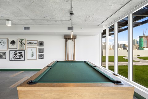 A pool table in a room with pictures on the wall.