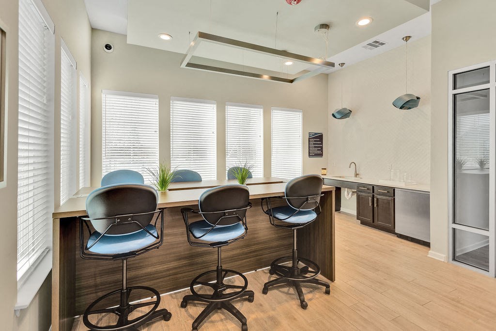 a room with a long counter with four blue chairs in front of it