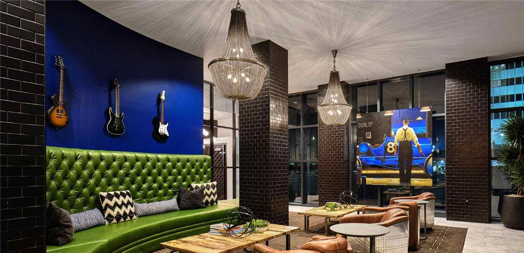 a room with a green couch and guitars on the wall  at Shearwood Station, New Rochelle, NY, 10801