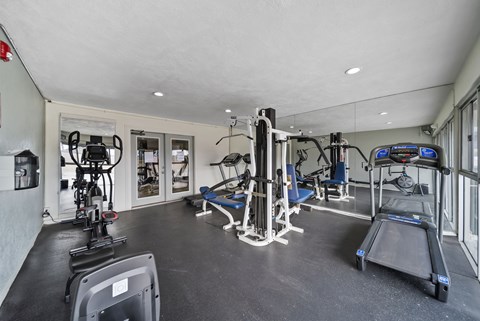 A gym with a variety of equipment including treadmills, weights, and exercise machines.