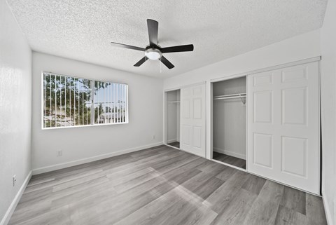 A room with a ceiling fan and a window with blinds.