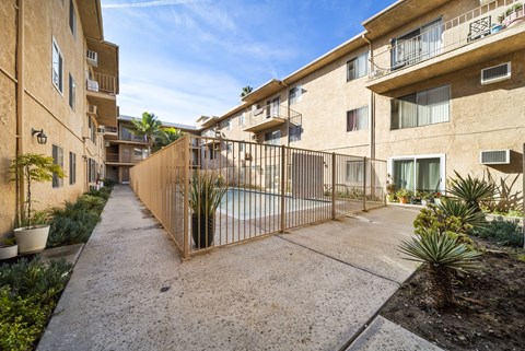 A sunny day at a residential complex with a pool and a fence.