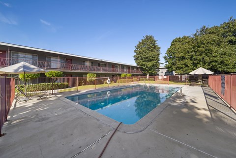 A swimming pool in front of a building with a red fence.