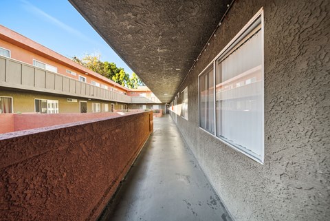 A long hallway with a red wall on the left and a concrete wall on the right.