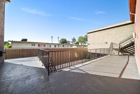 A courtyard with a metal railing and a staircase leading to a building.