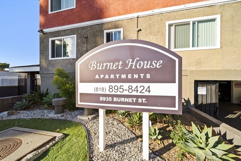 A sign for Burnet House Apartments is in front of a building.