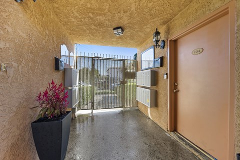 A hallway with a brown door and a black planter on the floor.