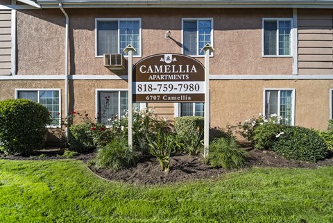 A sign for Cambellia Apartments stands in front of a building.
