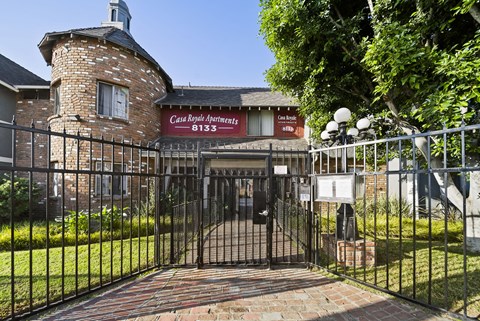 A black iron gate leads to a brick building with a sign that says Casa Royal Apartments.