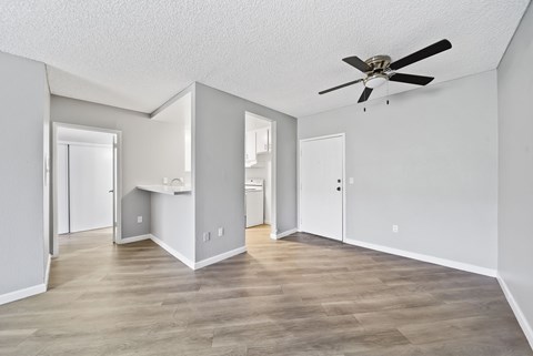 A spacious room with a ceiling fan and light wood flooring.