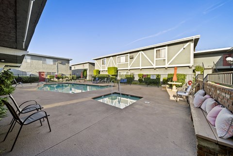 A pool surrounded by chairs and a fence.