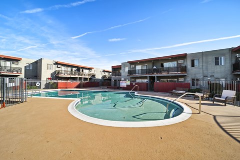 A round above ground pool with a white border and a brown sandy area around it.