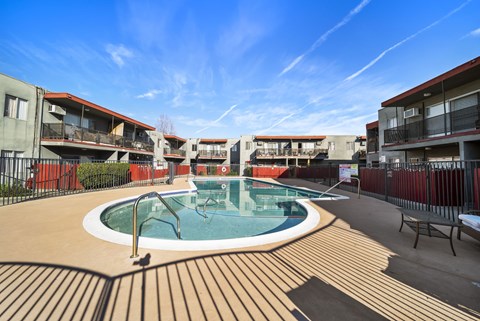 A swimming pool surrounded by a wooden deck and buildings.