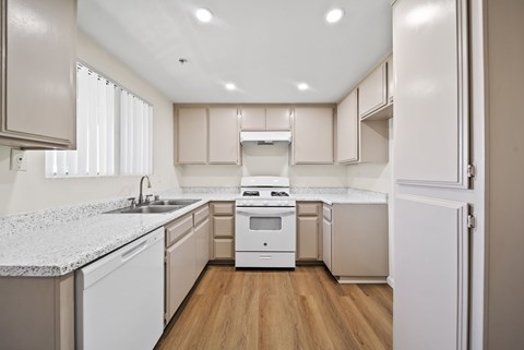 A kitchen with white appliances and wooden floors.