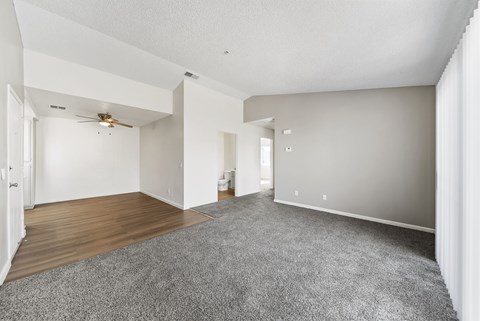 A spacious room with a ceiling fan and carpeted floor.