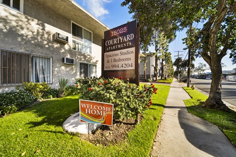 A sign for 16025 Courtyard Apartments is displayed in front of a building.