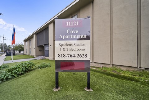 A sign for Cove Apartments is displayed in front of a building.
