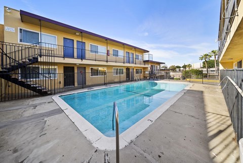 A swimming pool is surrounded by a concrete floor and a black fence.