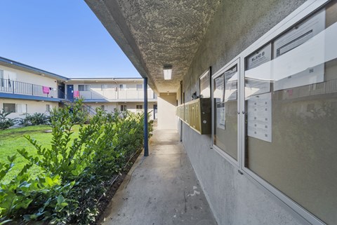 A long concrete walkway leads to a building with a balcony.