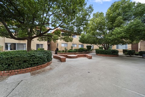 A courtyard with a brick wall and a tree in the middle.
