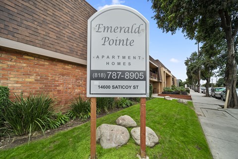 A sign for Emerald Pointe Apartment Homes stands in front of a brick building.