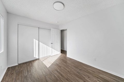 A room with white walls and wooden flooring with a door and a window.