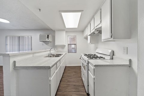 A white kitchen with a stove top oven and a sink.