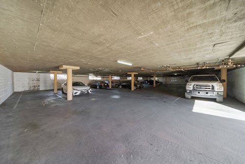 A parking garage with a white car and a brown truck.