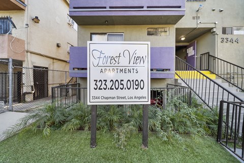 A sign for Forest View Apartments is in front of a building.