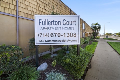 A sign for Fullerton Court Apartment Homes stands in front of a building.