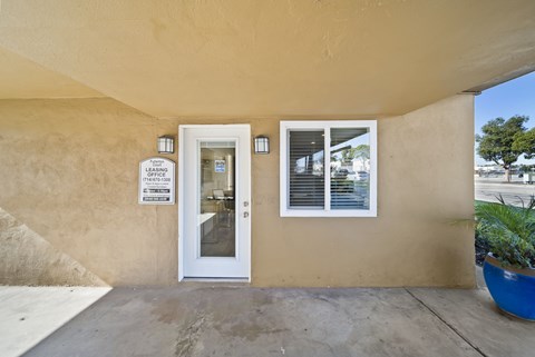 A beige building with a white door and a sign on the wall.