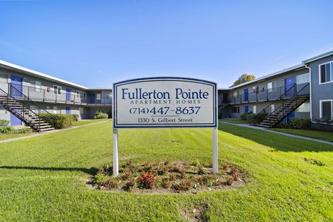 A sign for Fullerton Pointe Apartment Homes stands in front of apartment buildings.