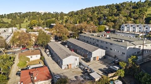 A large white building with a red roof is surrounded by other buildings and trees.