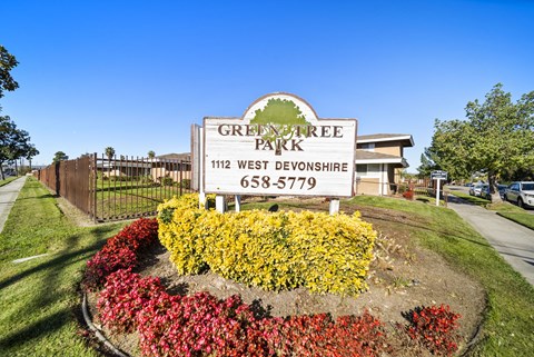 A sign for Green Tree Park in West Devonshire with a phone number on it.