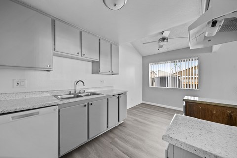 A kitchen with white cabinets and a marble countertop.