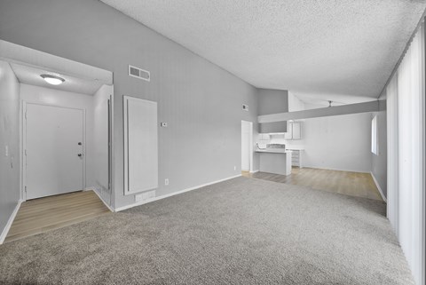 A spacious room with a carpeted floor and white walls.