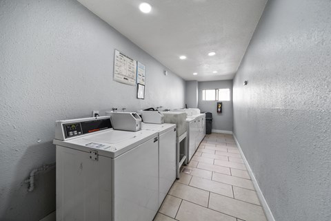 A clean, white-walled industrial kitchen with a row of white ovens and a white countertop.