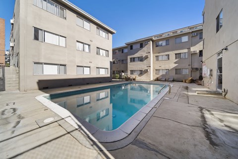 A swimming pool in a courtyard surrounded by buildings.