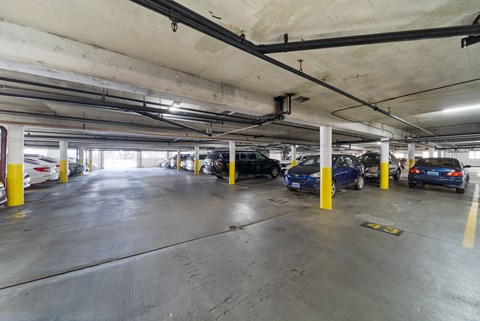 A parking garage with cars parked and yellow poles.