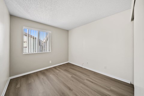 A room with a window and wooden flooring.