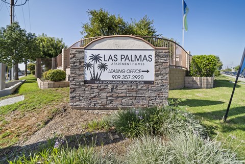 A sign for Las Palmas Apartment Homes with a phone number and address.