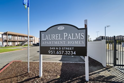 A sign for Laurel Palms Apartment Homes stands in front of a building.