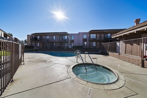 A sunny day at a pool with a building in the background.