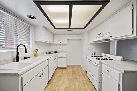 A white kitchen with a black ceiling and wooden floors.