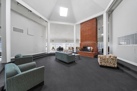 A living room with a grey couch and a red brick fireplace.