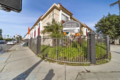 A sign for North Hills Village with a phone number is displayed on a fence.