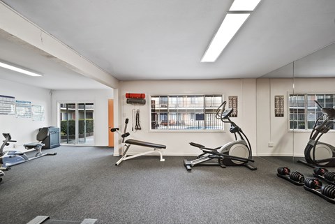 A gym with a variety of equipment including treadmills, weights, and exercise bikes.