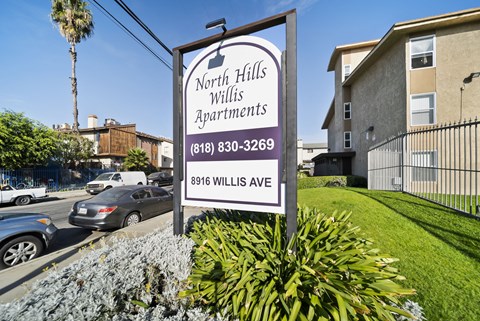 A sign for North Hills Willis Apartments is displayed in front of a building.